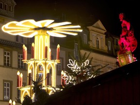 In this Tuesday, Dec. 4, 2018 photo a pyramid and an illuminated statue are seen at the traditional Christmas market in Heidelberg, Germany.  The Christmas market In the Old Town of Heidelberg underneath the famous castle is one of most picturesque christmas markets in southern Germany.