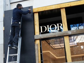 FILE - In this Friday, Nov. 30, 2018 file picture, a worker reinforces store windows on the famed Champs Elysees avenue to prepare for an expected protest by the "yellow jackets" on Saturday as a protest last weekend degenerated into violence, in Paris. One year and a half after he came into power, Macron is facing violent protests over rising taxes, high cost of living and his policies are criticized as favoring the rich.