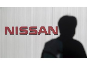 FILE- In this Nov. 21, 2018, file photo, a man walks past the logo of Nissan Motor Co. at Nissan Motor Co. Global Headquarters in Yokohama near Tokyo. Nissan, the Japanese automaker under scrutiny after its former chairman Carlos Ghosn was arrested on suspicion of financial misconduct, is recalling 150,000 vehicles spanning 11 models in Japan for dubious inspections for brakes and steering.
