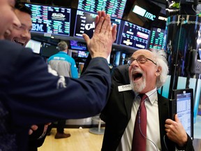 Traders Peter Tuchman, right, slaps a high five as the Dow closed up more than 1,000 points in best day for Wall Street in 10 years on Wednesday, Dec. 26.