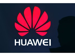 A man is silhouetted as he walks by a Huawei retail store at a shopping mall in Beijing, Tuesday, Dec. 11, 2018. China's foreign minister vowed Tuesday to protect its citizens abroad as a Canadian court decided whether to release a technology executive on bail in a case that has riled U.S.-Chinese relations.
