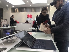 Foreigners look at a Huawei computer at a Huawei store in Beijing, China, Thursday, Dec. 6, 2018. Canadian authorities said Wednesday that they have arrested the chief financial officer of China's Huawei Technologies for possible extradition to the United States.