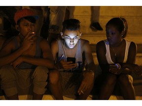 FILE - In this July 1, 2015 file photo, youths use a password protected wifi network coming from a five star hotel to surf the Internet on their smart phones in downtown Havana, Cuba. Cuba's government announced on Tuesday, Dec. 4, 2018 that its citizens will be offered full internet access on mobile phones starting Thursday, Dec. 6, becoming one of the last nations to do so.