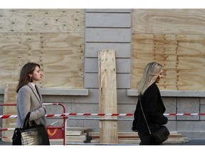 Women walk past barricaded shop windows on the Champs Elysees avenue, in Paris, Friday, Nov. 30, 2018. Workers were barricading shop windows along Paris' famed Champs-Elysees Avenue on Friday, a day before a protest against government fuel tax hikes and other measures seen as hurting average citizens. A demonstration on the avenue a week earlier degenerated into violence and police used tear gas and water cannons to regain control.