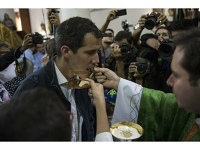 Opposition National Assembly leader Juan Guaido, who declared himself interim president, receives communion during Mass at a church in Caracas, Venezuela, Sunday, Jan. 27, 2019. Guaido says he is acting in accordance with two articles of the constitution that give the National Assembly president the right to hold power temporarily and call new elections.