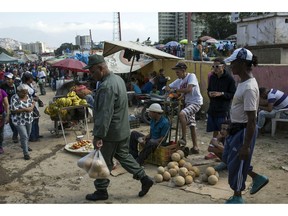 Workers and customers gather at a wholesale food market in Caracas, Venezuela, Monday, Jan. 28, 2019. Economists agree that the longer the standoff between the U.S.-backed opposition leader Juan Guaido and President Nicolas Maduro drags on, the more regular Venezuelans are likely to suffer.