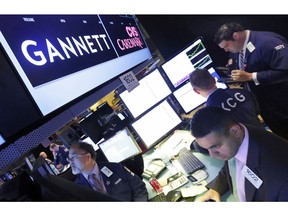 FILE - In this Aug. 5, 2014, file photo, specialist Michael Cacace, foreground right, works at the post that handles Gannett on the floor of the New York Stock Exchange. The Wall Street Journal is reporting that MNG Enterprises, better known as Digital First Media, is preparing to bid for newspaper publisher Gannett Co.