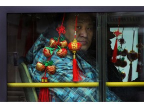 FILE - In this Monday, Jan. 7, 2019, file photo, a commuter looks out from a bus window decorated with Chinese New Year decoration traveling on a road in Beijing. The United States and China have held their first face-to-face trade talks since Presidents Donald Trump and Xi Jinping agreed on Dec. 1 to postpone further tariff increases in a fight over technology between the two biggest economies.