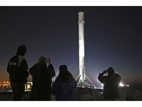 FILE - In this Jan. 17, 2017 file photo, people photograph the SpaceX Falcon 9 rocket booster as it makes its way into the port of Los Angeles. SpaceX says it will build its Mars spaceship in south Texas instead of the Port of Los Angeles, dealing another blow to the local economy only days after the company announced massive layoffs. The Southern California-based company announced Wednesday, Jan. 16, 2019 that test versions of its Starship and Super Heavy rocket will be assembled at its Texas launch facility in a move to streamline operations.
