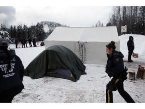 RCMP members gather at a Wet'suwet'en checkpoint after representatives from Coastal GasLink and contractors make their way through an exclusion zone at the 27 kilometre marker towards the Unist'ot'en camp to remove barriers on a bridge over the Morice River, southwest of Houston, B.C., on Friday, January 11, 2019.