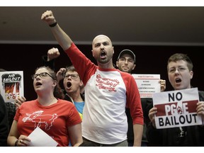 Brandon Harami, center, and others yell during a California Public Utilities Commission meeting in San Francisco, Monday, Jan. 28, 2019. California regulators have approved a measure allowing Pacific Gas & Electric Corp. to immediately obtain credit and loans while the company is under Chapter 11 bankruptcy protection.