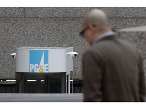 A man crosses the street in front of a Pacific Gas and Electric building in San Francisco, Tuesday, Jan. 29, 2019. Faced with potentially ruinous lawsuits over California's recent wildfires, Pacific Gas & Electric Corp. filed for bankruptcy protection Tuesday in a move that could lead to higher bills for customers of the nation's biggest utility and reduce the size of any payouts to fire victims.