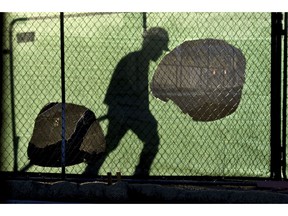 FILE - In this Nov. 14, 2018 file photo, the shadow of a worker falls on a fence at the construction site of a convenience store in Victorville, Calif. On Wednesday, Jan. 16, 2019, the Federal Reserve releases its latest "Beige Book" survey of economic conditions. The Beige Book is based on anecdotal reports from businesses and will be considered along with other data when Fed policymakers meet next.