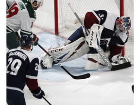 Colorado Avalanche goaltender Philipp Grubauer, right, stops a shot by Minnesota Wild center Luke Kunin, top left, as Colorado center Nathan MacKinnon defends in the third period of an NHL hockey game, Wednesday, Jan. 23, 2019, in Denver. The Wild won 5-2.
