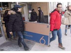 Two men carry a large screen television from an electronics store during Boxing Day sales in Montreal, Wednesday, Dec. 26, 2018. Statistics Canada says retail sales fell 0.9 per cent to $50.4 billion in November.