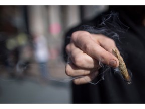 A person holds a joint while smoking marijuana to celebrate the legalization of recreational cannabis, in Vancouver, on Wednesday October 17, 2018.