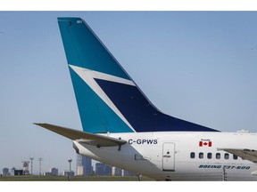 The tail of a WestJet plane is seen dwarfing the Calgary skyline before the airline's annual meeting in Calgary, Tuesday, May 3, 2016. The Transportation Safety Board says an onboard fire that forced a WestJet plane to return to the Calgary International Airport soon after takeoff last June was caused by spare e-cigarette lithium-ion batteries that a passenger failed to declare in his checked baggage.