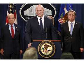 Acting Attorney General Matt Whitaker, center, smiles at a question from a reporter after an announcement of an indictment of Chinese telecommunications companies including Huawei, on violations including bank and wire fraud, Monday, Jan. 28, 2019, at the Justice Department in Washington. At left is Commerce Secretary Wilbur Ross, and FBI Director Christopher Wray, at right.