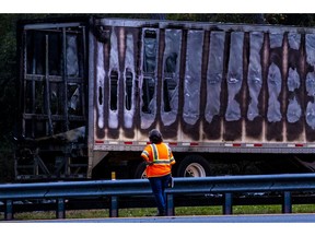 FILE - In this Thursday, Jan. 3, 2019, file photo, a worker looks at a charred semitrailer after a wreck with multiple fatalities on Interstate 75, south of Alachua, near Gainesville, Fla. The 35-day partial government shutdown stopped the National Transportation Safety Board from dispatching investigators to 22 accidents that killed 30 people, jeopardizing some perishable evidence, the agency said Monday, Jan. 28, 2019.