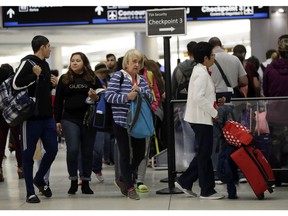 Passengers wait in line at a security checkpoint at Miami International Airport, Friday, Jan. 18, 2019, in Miami. The three-day holiday weekend is likely to bring bigger airport crowds.