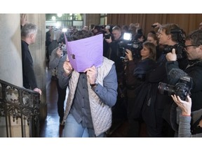 A defendant covers his face when arriving at the court in Berlin, Germany, Thursday, Jan. 10, 2019 for the first day of the trial over the brazen theft of a 100-kilogram (221-pound) Canadian gold coin from a Berlin museum. The "Big Maple Leaf" coin, worth several million dollars, was stolen from the Bode Museum in March 2017.