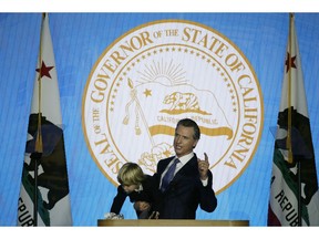 In this Monday, Jan. 7, 2019, photo, California Gov. Gavin Newsom holds his son Dutch while giving his address at his inauguration in Sacramento, Calif. Newsom gets his chance this week to show how he'll resolve a central tension in his platform: advancing expensive new programs while maintaining robust savings.