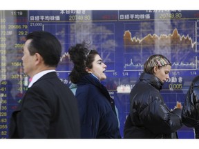 People walk by an electronic stock board of a securities firm in Tokyo, Monday, Jan. 21, 2019. Shares in Asia rose Monday, extending gains on Wall Street last week. Buying enthusiasm has been spurred by renewed hopes for progress on resolving the trade standoff between the U.S. and China. Shares rose in Shanghai and Hong Kong early Monday despite news that China's economy grew at its lowest pace in three decades last year.