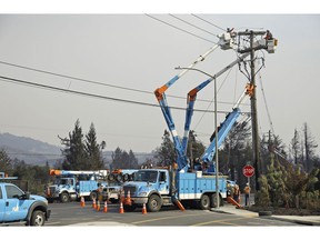 FILE - In this Oct. 11, 2017 file photo, a Pacific Gas & Electric crew works at restoring power along the Old Redwood Highway in Santa Rosa, Calif. Pacific Gas & Electric Co. was not the first utility to declare bankruptcy, not even when it did so in 2001. But when the nation's largest utility filed again for Chapter 11 protection this week, it took a step no utility has in seeking shelter from potentially insurmountable legal bills because the company's power lines are blamed for sparking deadly wildfires.