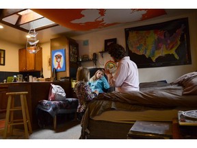 FILE - In this Nov. 28, 2017, file photo, TC Bell sits with his two daughters Dagny, and Emma, before they get dressed for school, at their home in Denver. Bell's daughters were then recipients of the Children's Health Insurance Program or CHIP, which is a program that provides low-cost coverage to families who earn too much to qualify for Medicaid. Health care proposals are among the first actions for some new Democratic governors and Democratically controlled legislatures.