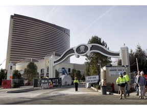 In this Wednesday, Jan. 2, 2019 photo workers stand near an entrance to the under-construction Encore Boston Harbor luxury resort and casino, in Everett, Mass. A Nevada judge was being asked Friday, Jan. 4 to let the Massachusetts Gaming Commission make public a report on allegations of sexual misconduct against former casino mogul Steve Wynn. A decision could affect a decision on a pending license for the $2 billion casino and hotel being built in Everett.