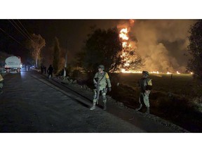 In this image provided by the Secretary of National Defense, soldiers guard in the area near an oil pipeline explosion in Tlahuelilpan, Hidalgo state, Mexico, Friday, Jan. 18, 2019. A huge fire exploded at a pipeline leaking fuel in central Mexico on Friday, killing at least 21 people and badly burning 71 others as locals were collecting the spilling gasoline in buckets and garbage cans, officials said. Officials said the leak was caused by an illegal tap that fuel thieves had drilled into the pipeline in a small town in the state of Hidalgo, about 62 miles (100 kilometers) north of Mexico City. (Secretary of National Defense via AP)