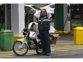 A postal worker whose motorcycle ran out of gas stands at a closed gas station in Mexico City, Monday, Jan. 14, 2019. Mexico President Andres Manuel Lopez Obrador has vowed to get the upper hand on fuel thieves and is trying to choke off their supply by taking several major pipelines off line. However, tanker trucks used to deliver the fuel couldn't distribute fuel at the same levels as the pipelines, triggering shortages and panic buying.