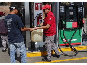 A gasoline attendant sells gas to a client who filled up a container in Tepotzotlan, Mexico, Wednesday, Jan. 9, 2019. A fuel scarcity arose after President Andres Manuel Lopez Obrador decided to close government pipelines riddled with illegal fuel taps drilled by thieves, and instead deliver gas and diesel by tanker trucks.