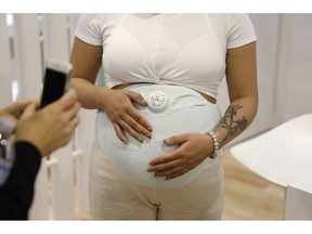 A model wears the Owlet Band pregnancy monitor at the Owlet booth at CES International, Wednesday, Jan. 9, 2019, in Las Vegas. The device can track fetal heart rate, kicks and contractions.