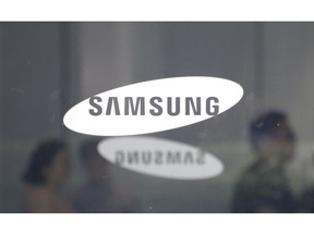 FILE - In this July 31, 2018 file photo, employees walk past logos of the Samsung Electronics Co. at its office in Seoul, South Korea,  Samsung is giving a weak fourth-quarter operating profit forecast, as the smartphone and memory chip maker contends with increased competition and softer chip demand.  The announcement, Monday, Jan. 7, 2019,  follows Apple's disclosure that its revenue for the last quarter of 2018 will fall well below projections, a decrease the company traced mainly to China. Apple is one of Samsung's chip customers.