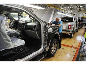 FILE- In this Sept. 27, 2018, file photo a United Auto Workers assemblyman works on a 2018 Ford F-150 truck being assembled at the Ford Rouge assembly plant in Dearborn, Mich. Ford Motor Co. reports financial results Wednesday, Jan. 23, 2019.