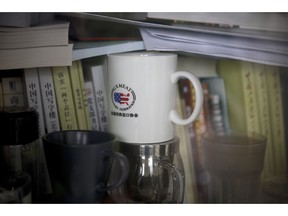 FILE- In this Dec. 3, 2018, photo, a cup baring the logo of U.S. Meat Export Federation is placed inside a bookshelf at an office in the Beijing International Club. The Trump administration and China are facing growing pressure to blink in their six-month stare-down over trade because of jittery markets and portents of economic weakness. The longer their trade war lasts, the longer companies and consumers will feel the pain of higher-priced imports and exports.