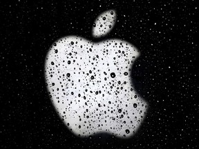 FILE- In this Dec. 26, 2018, file photo an Apple logo is seen in raindrops on a window outside an Apple Store at the Country Club Plaza shopping district in Kansas City, Mo. Apple is reducing the size of its workforce assigned to driverless car technology as the company reorganizes amid weakening sales of iPhones, its biggest moneymaker. The company acknowledged the cutbacks in a Thursday, Jan. 24, 2019, statement, without specifying the number of jobs affected. CNBC reported that more than 200 employees were dismissed from Apple's self-driving car division, known internally as "Project Titan." (AP Photo/Charlie Riedel, File)