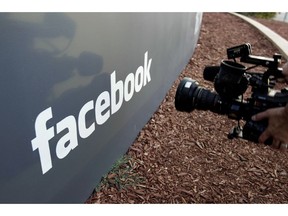 FILE- In this May 18, 2012, file photo a television photographer shoots the sign outside of Facebook headquarters in Menlo Park, Calif. Facebook says it has removed 783 Iran-linked pages, accounts and groups from its service for what it calls "coordinated inauthentic behavior," that is, misrepresenting who is running the accounts with the intent of disrupting politics and elections.