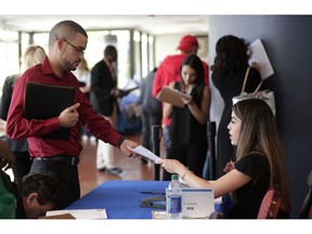 FILE- In this Jan. 30, 2018, file photo, an employee of Aldi, right, takes an application from a job applicant at a JobNewsUSA job fair in Miami Lakes, Fla. On Thursday, Jan. 3, 2019, payroll processor ADP reports how many jobs private employers added in December.