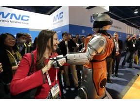 FILE- In this Jan. 6, 2015, file photo Danielle London, left, dances with a performer dressed as a robot at the Alibaba.com booth at the International CES in Las Vegas. The CES 2019 gadget show, which kicks off Sunday, will showcase the expanding influence and sway of China's rapidly growing technology sector. Chinese tech giants like Baidu and Alibaba have made flashy presentations at CES in recent years. Roughly 40 percent of all exhibitors planning to showcase their latest technology at this week's Las Vegas event are Chinese firms, second only to the U.S. in sheer numbers.
