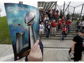 FILE - In this Feb. 5, 2017, file photo, a sales person holds up a program as fans arrive at NRG Stadium before NFL football's Super Bowl 51 between the Atlanta Falcons and the New England Patriots in Houston. of you're headed to the Super Bowl some year in the future, and you're wondering how much cash you'll need for the big game. No worries: During its sponsorship renewal with the NFL through the 2025 season, Visa envisions the first cashless Super Bowl.