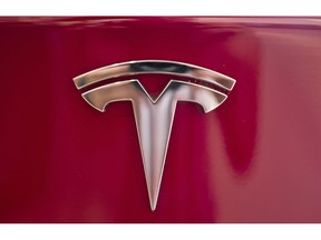 FILE- This Aug. 8, 2018, file photo shows a Tesla emblem on the back end of a Model S in the Tesla showroom in Santa Monica, Calif. The parents of a Florida teenager killed when a Telsa sedan crashed and caught fire last year are suing the electric car company alleging that the battery pack on its electric Model S is defective and can erupt into intense fires.