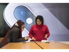 An image of an iPhone is on display in the background as a customer, left, is helped at the Apple store in the Brooklyn borough of New York, Thursday, Jan. 3, 2019. Apple's shock warning that its Chinese sales are weakening ratcheted up concerns about the world's second largest economy and weighed heavily on global stock markets as well as the dollar on Thursday.