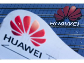 FILE - This Tuesday, Dec. 18, 2018, file photo, shows company signage on display near the Huawei office building at its research and development center in Dongguan, in south China's Guangdong province. A federal indictment accuses Huawei of stealing trade secrets from T-Mobile, in the form of a robot designed to automatically test phones for problems.