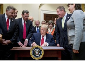 FILE - In this Tuesday, Feb. 28, 2017, file photo, President Donald Trump signs the Waters of the United States (WOTUS) executive order, in the Roosevelt Room in the White House in Washington, which directs the Environmental Protection Agency to withdraw the WOTUS rule, which expands the number of waterways that are federally protected under the Clean Water Act. Trump often points to farmers as among the biggest winners from the administration's proposed rollback of federal protections for wetlands and waterways across the country. But under longstanding federal law and rules, farmers and farm land already are exempt from most of the regulatory hurdles on behalf of wetlands that the Trump administration is targeting.