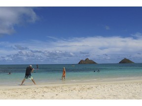 FILE - This Oct. 29, 2013 file photo shows tourists on Lanikai Beach in Kailua, Hawaii. Airbnb is pushing back against Hawaii's attempt to find tax delinquents by subpoenaing 10 years' worth of invoices, receipts and other records from the home-sharing platform's island hosts, calling it an unprecedented, "massive intrusion" that violates state and federal law.
