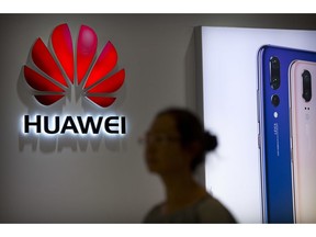 FILE - In this July 4, 2018, file photo, a shopper walks past a Huawei store at a shopping mall in Beijing. Chinese telecom equipment giant Huawei unveiled Monday, Jan. 7, 2019, a processor chip for data centers and cloud computing in a bid to expand into an emerging global market despite Western warnings the company might be a security risk.