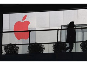 In this Dec. 6, 2018, photo, a woman runs past a Apple logo colored red in Beijing, China. Apple Inc.'s $1,000 iPhone is a tough sell to Chinese consumers who are jittery over an economic slump and a trade war with Washington. The tech giant became the latest global company to collide with Chinese consumer anxiety when CEO Tim Cook said iPhone demand is waning, due mostly to China. Weak consumer demand in the world's second-largest economy is a blow to industries from autos to designer clothing that are counting on China to drive revenue growth.