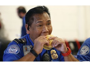 TSA employee Hill Dalde eats a hamburger during lunch at Salt Lake City International Airport, Wednesday, Jan. 16, 2019, in Salt Lake City. In Salt Lake City, airport officials treated workers from the TSA, FAA and Customs and Border Protection to a free barbecue lunch as a gesture to keep their spirits up during a difficult time.